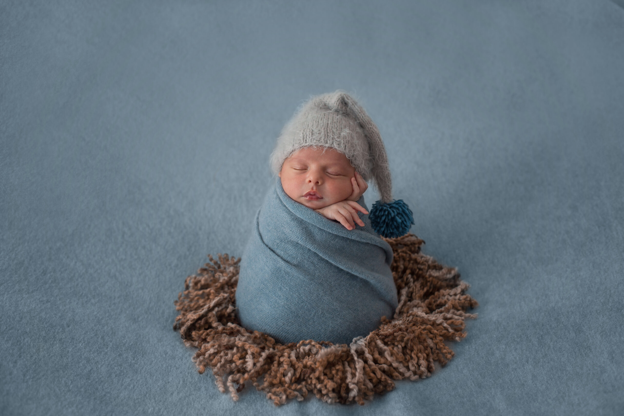 newborn baby with white beret wrapped with blue shawl scaled